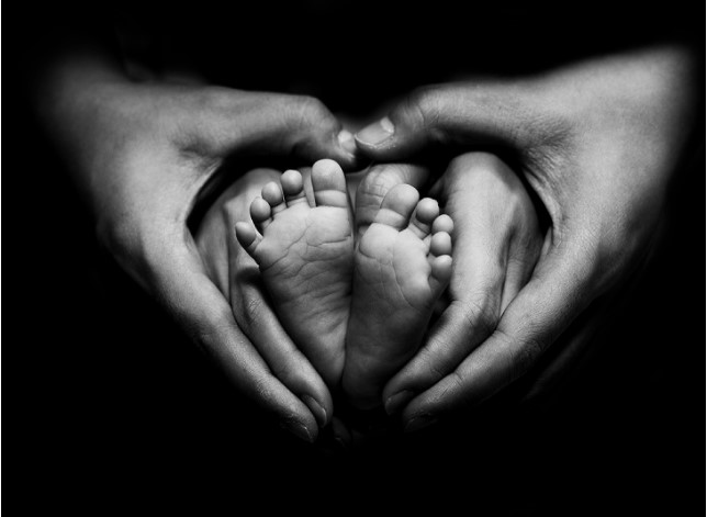 Infant feet held by hands
