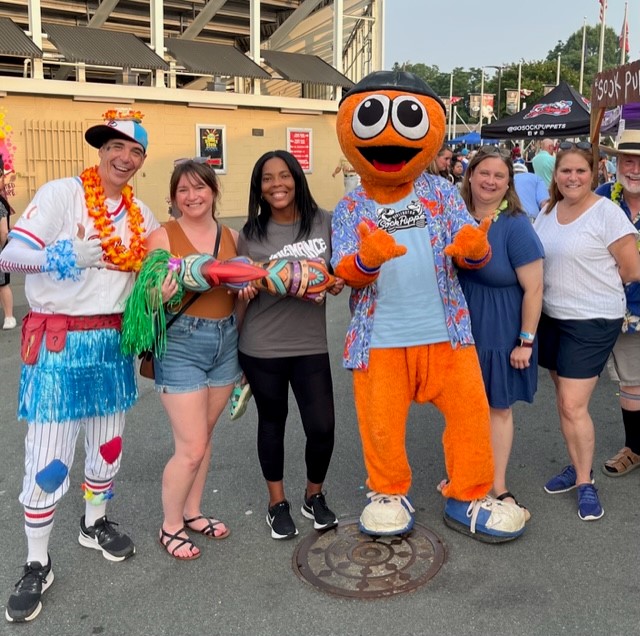 Employees with mascots at Sock Puppets Baseball Game