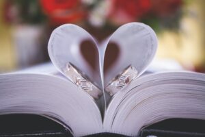 Photo of open book, with pages making a heart, and rings laid in the heart. Photo by Alejandro Avila, found on Pexels.com
