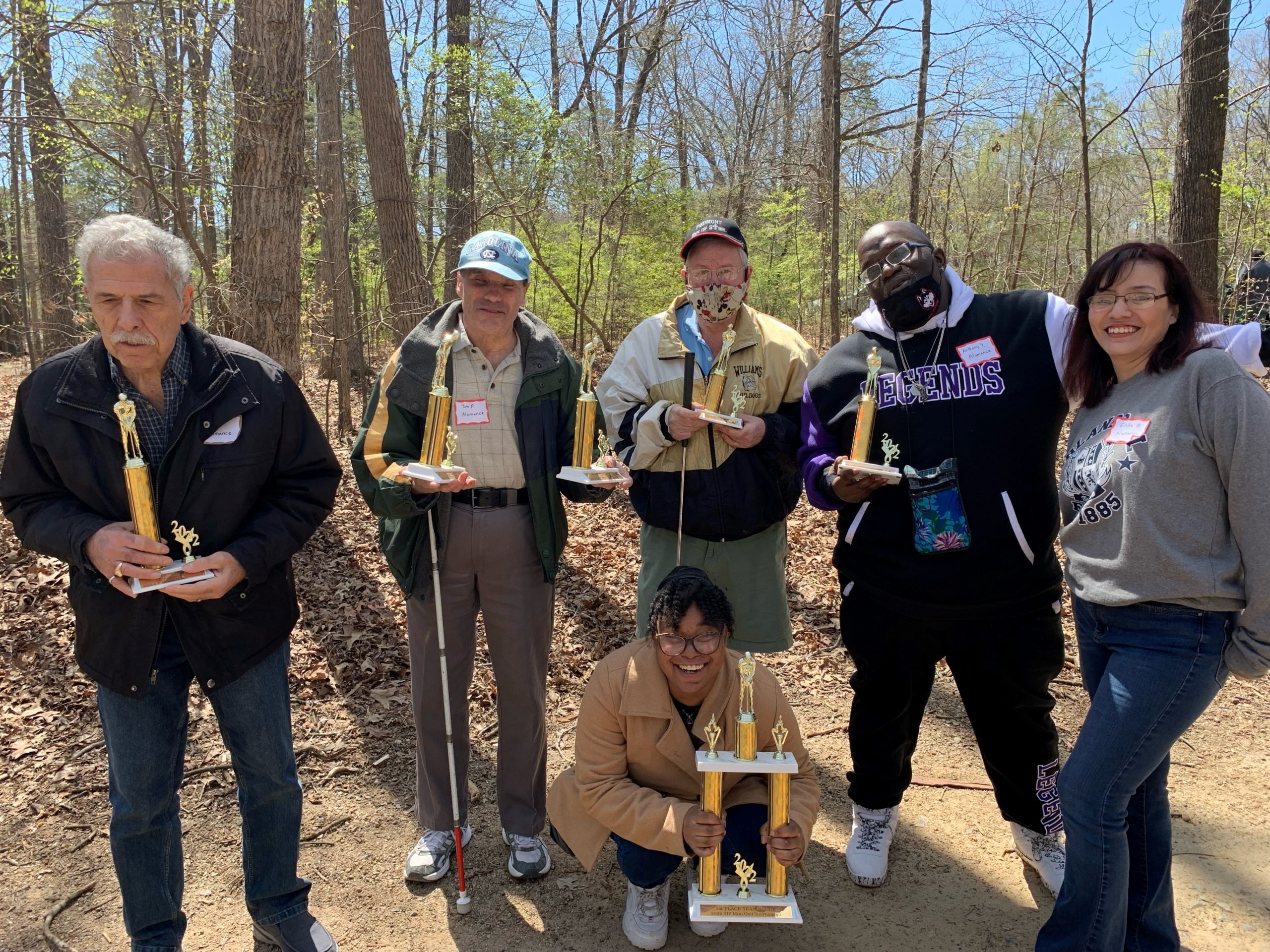 4 Visually Impaired Program participants hold trophies received at a putt putt tournament 